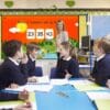 Pupils Sitting At Table As Teacher Stands By Whiteboard